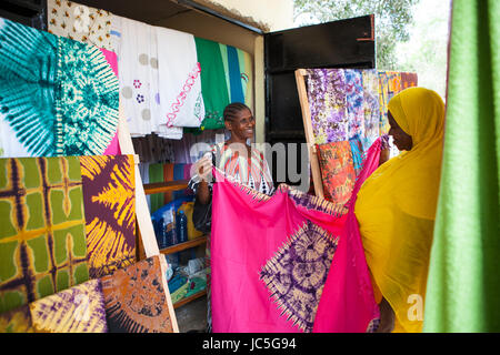 Salma Likupila (rechts) im Gespräch mit Kunden in ihrem Shop eine weibliche Kleinunternehmen Batik-Shop-Betreiber mit einem Kunden, Tansania, Afrika. Stockfoto