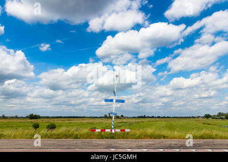 Typisch holländischen flache Landschaft mit Blick auf die Polder und eine Straße mit Schild auf einem sonnigen Tag unter einem blauen bewölkten Himmel. Maarsseveen, Niederlande. Stockfoto