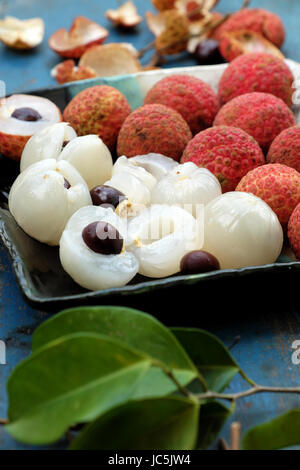 Obstteller auf blauem Hintergrund, Litschi oder Lychee Früchte oder Vai Thieu hautnah. Rote Früchte schälen mit saftigen Fruchtfleisch in weiß, süß und lecker Stockfoto