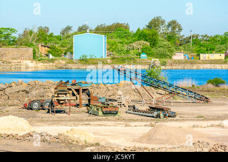 Sammlung von gebrauchten Maschinen in einem Kalksteinbruch mit Wasser gefüllte Grube im Hintergrund. Stockfoto