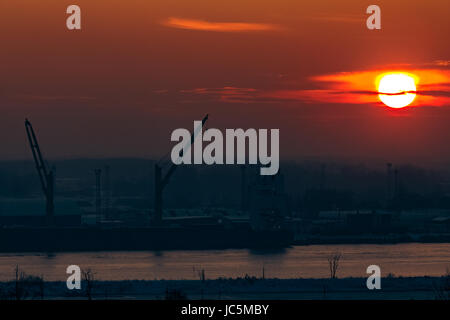 Heiße orange Sonnenuntergang über dem Fluss. Stadtlandschaft Stockfoto