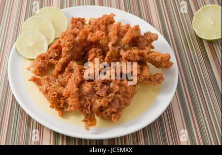 Snack und Dessert, Thai traditionelle Snacks knusprig gebratene Hähnchen Skins mit frischer Limette auf einem weißen Teller serviert. Stockfoto