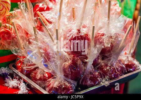 Sweet glasiert rote Toffee Liebesäpfel auf Sticks für den Verkauf auf dem Wochenmarkt oder Jahrmarkt. Köstliche rote Liebesäpfel mit bunten Streuseln bedeckt. Stockfoto