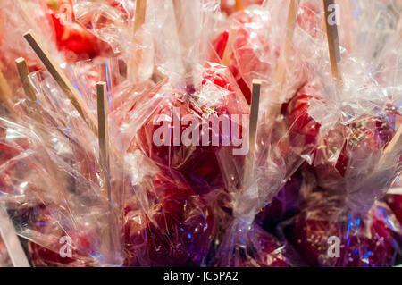 Sweet glasiert rote Toffee Liebesäpfel auf Sticks für den Verkauf auf dem Wochenmarkt oder Jahrmarkt. Köstliche rote Liebesäpfel mit bunten Streuseln bedeckt. Stockfoto