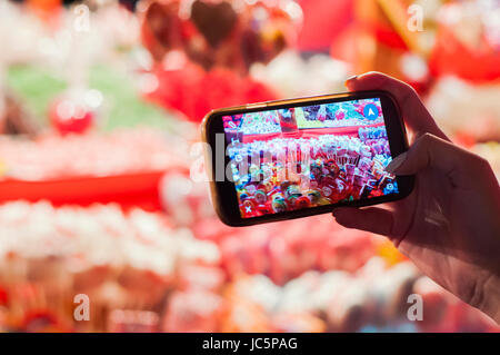 Stall mit traditionellen bunten und festlichen Bonbons am Weihnachtsmarkt, viele bunte Bonbons und Lutscher auf Messe. Mädchen mit Smartphone-Fotografie Stockfoto