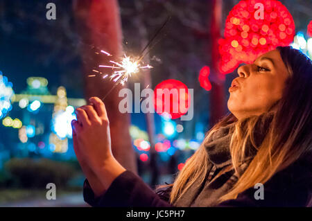 Frau mit Wunderkerze in der Hand, Silvester zu feiern. Junge Frau, die einen feiern das neue Jahr steht vor der Tür. Sie hält glitzernden sparkl Stockfoto
