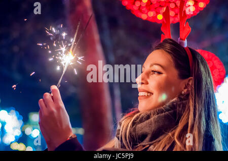 Frau mit bengalischen Lichtern über Bokeh Hintergrund. Weihnachten-Konzept.  Nahaufnahme einer schönen Frau mit Wunderkerze. Stockfoto