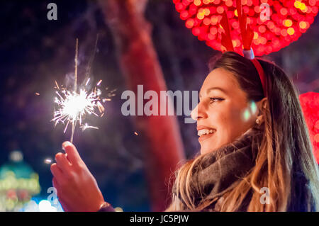 Frau mit bengalischen Lichtern über Bokeh Hintergrund. Weihnachten-Konzept.  Nahaufnahme einer schönen Frau mit Wunderkerze. Stockfoto