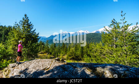 Frau betrachten die Tantalus Bergkette mit schneebedeckten Gipfeln von Alpha Berg, Serratus und Tantalus Berge entlang der Duffy Lake Rd Stockfoto