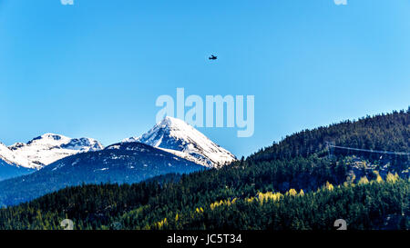 Kleines Flugzeug über Grüne See in der Nähe von Whistler, British Columbia, Kanada fliegen, mit dem Schnee caped peak Keil Berg im Hintergrund Stockfoto