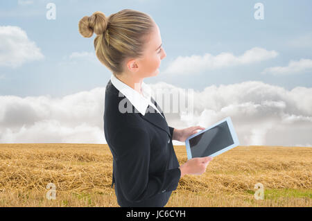 Zusammengesetztes Bild der blonden Geschäftsfrau hält neue tablet Stockfoto