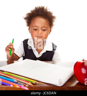 Porträt von niedlichen kleinen afrikanischen Schuljunge hinter Schreibtisch sitzt und mit bunten Bleistift malen für Mittagessen großer roter Apfel, glückliche Schüler Konzept Stockfoto