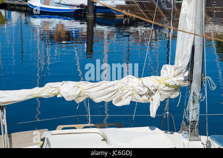 Segel auf einem kleinen Segelboot in einem Hafen gerollt Stockfoto