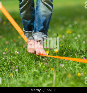 Guy üben Slackline im Stadtpark. Slacklinen ist eine Praxis in der Balance, die in der Regel, Nylon oder Polyester Gurtband zwischen zwei Ankerpunkten gespannt verwendet. Stockfoto