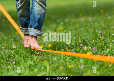 Guy üben Slackline im Stadtpark. Slacklinen ist eine Praxis in der Balance, die in der Regel, Nylon oder Polyester Gurtband zwischen zwei Ankerpunkten gespannt verwendet. Stockfoto