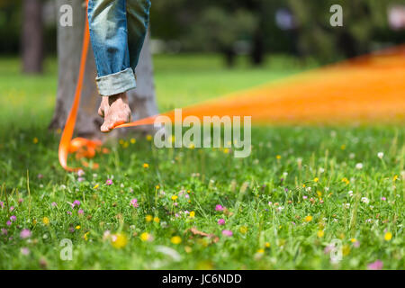 Guy üben Slackline im Stadtpark. Slacklinen ist eine Praxis in der Balance, die in der Regel, Nylon oder Polyester Gurtband zwischen zwei Ankerpunkten gespannt verwendet. Stockfoto