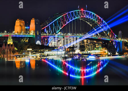 Multi Farbe Bogen der Sydney Harbour Bridge mit unscharfen Reflexion bei Vivid Sydney Festival im Jahr 2017. Blaue Lichtstrahlen markieren Sydney CBD. Stockfoto