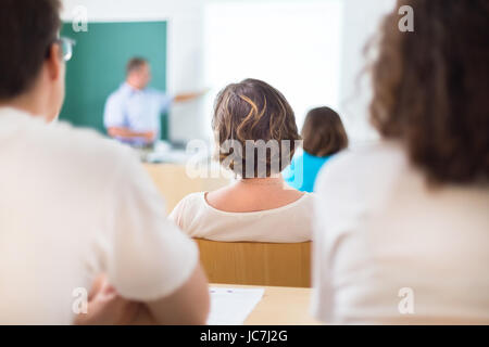 Lehrer an der Universität vor einem Whiteboard-Bildschirm. Schüler hören um zu belehren und sich Notizen macht. Stockfoto