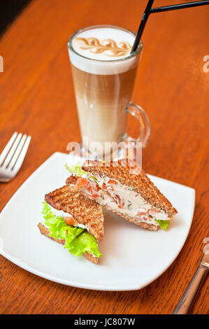 Sandwich mit Käse und Lachs und Gemüse mit latte Stockfoto