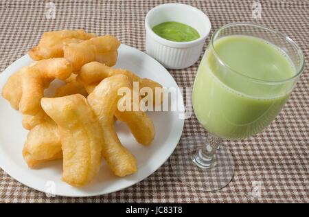 Snack und Dessert, chinesische traditionelle Snacks Deep Fried Doughstick auf einem weißen Teller serviert mit Pandan Pudding Tauchen und grüne Soja-Milch. Stockfoto