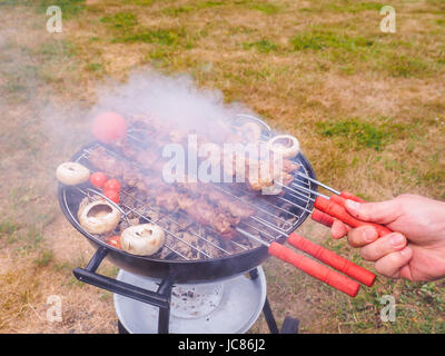 Nahaufnahme eines Kochs heißen Grill Spieße mit Fleisch einschalten Stockfoto