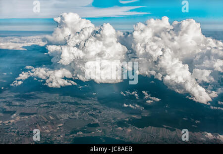 Blick auf Wolken und Land vom Flugzeugfenster aus großer Höhe. Stockfoto