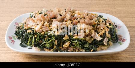 Chinesische traditionelle Speisen, Teller mit Stir-Fried-Jute verlässt oder Mulukhiyah Blätter mit gehacktem Schweinefleisch, Knoblauch und fermentierte Soja-Bohne. Stockfoto