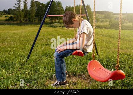 Traurig einsam Junge sitzt auf Schaukel allein Stockfoto