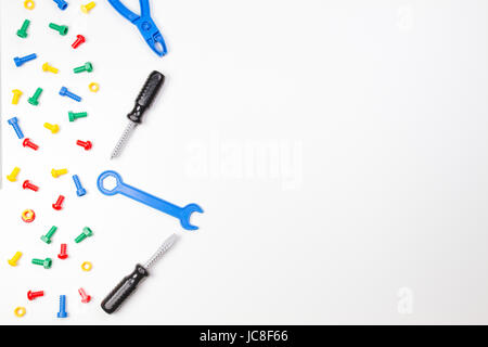 Bunte Kinder Spielzeug Grenze. Kunststoff Spielzeug Werkzeuge, Schrauben und Muttern auf weißem Hintergrund als Frame. top View Stockfoto
