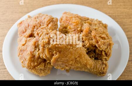 Küche und Essen, einen Teller mit knusprig gebratenes Huhn auf braunen Holztisch. Stockfoto