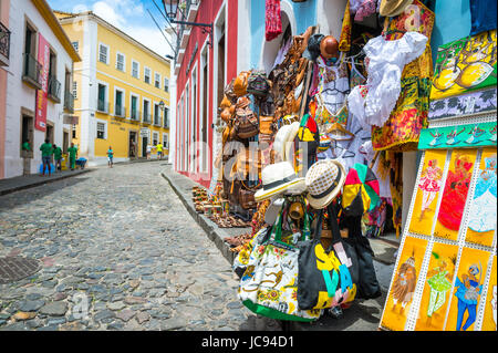 SALVADOR, Brasilien - 9. März 2017: Souvenirläden verkaufende Taschen und lokales Kunsthandwerk säumen die traditionellen kopfsteingepflasterten Straßen des historischen touristischen d Stockfoto