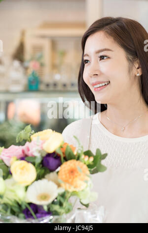 Porträt des jungen lächelnde Frau mit Blumen Stockfoto