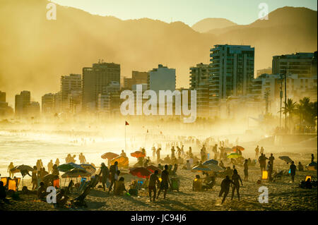 RIO DE JANEIRO - 20. März 2017: Silhouetten von Menschen Enjoing golden nebeligen Sonnenuntergang Ufer der Strand von Ipanema in Rio De Janeiro, Brasilien Stockfoto