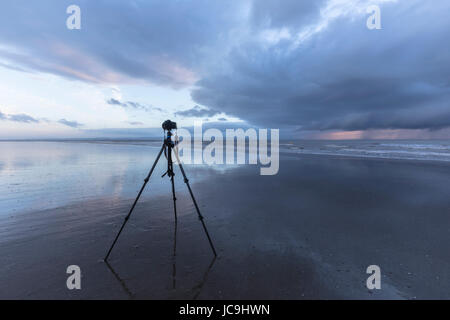 Kamera auf einem Stativ bei Ebbe am Strand warten auf den Sonnenuntergang erfassen Stockfoto