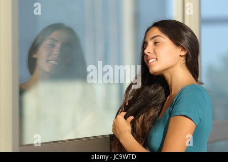 Flirty Teengirl kämmt mit einem Fenster wie ein Spiegel im Freien auf der Straße Stockfoto