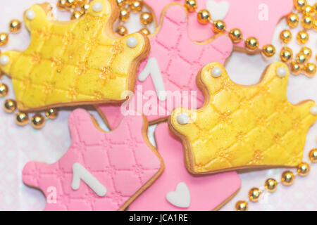 Der erste Geburtstag des Royal icing Cookies - Rosa und Golden Crown geformte Cookies mit der Nummer 1. Stockfoto