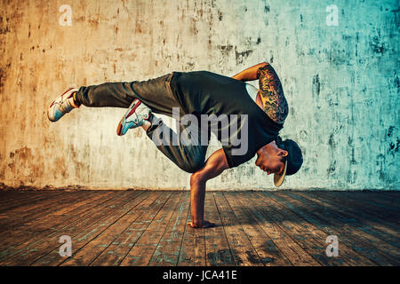 Junger Mann Breakdance auf Wand Hintergrund. Lebendigen Farben Effekt. Tattoo auf den Körper. Stockfoto