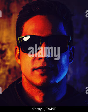 Junge cool Mann in Sonnenbrille Closeup Portrait. Kontrast und gesättigte rote und blaue Farben dramatischen Stil. Stockfoto