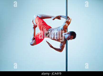 Junge starke Pole dance Mann auf Wand Hintergrund Stockfoto