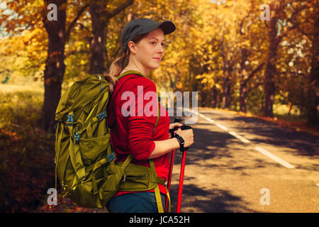 Junge Frau Touristen zu Fuß mit Stöcke und Rucksack unterwegs im Herbst Stockfoto