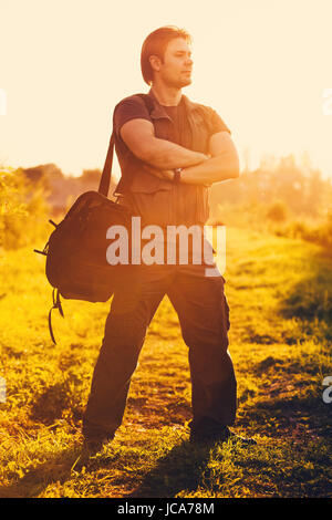 Junger Mann Touristen mit großen Umhängetasche stehen im Abendlicht Stockfoto