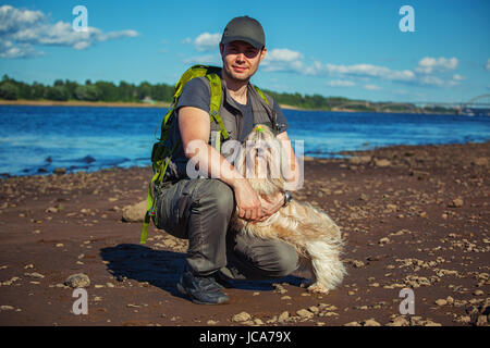 Junger Mann Tourist mit Shih-Tzu Hund am Ufer Stockfoto