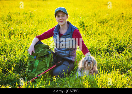 Junge Frau Tourist mit Shih Tzu Hund ruhen Sie sich nach Reisen im Feld mit Abendlicht Stockfoto