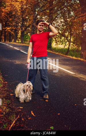 Junger Mann Tourist wandern mit Hund unterwegs. Warmen Sonnenuntergang Farben. Stockfoto