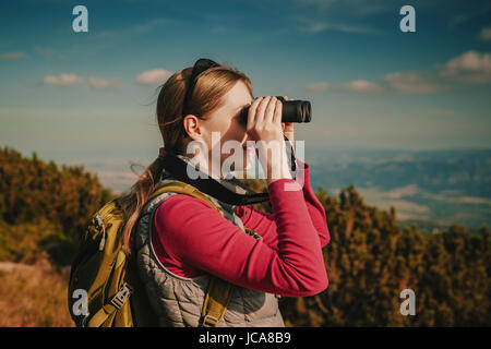 Junge Frau Tourist mit dem Fernglas suchen in den Bergen Stockfoto