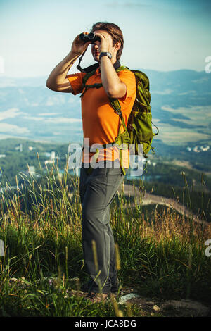 Junger Mann Tourist mit dem Fernglas suchen in den Bergen Stockfoto