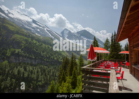 Ein Lodge-Deck mit roten Sonnenschirmen mit Blick auf die Schweizer Alpen.  Kandersteg, Schweiz. Stockfoto