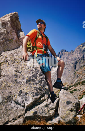 Junger Mann touristischen Stand an hohen Bergen und sah zur Seite Stockfoto