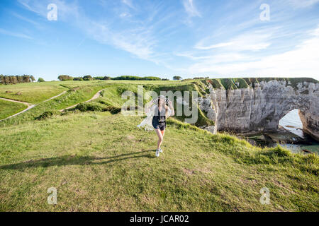 Junge Frau in gestreiften Hut und Pullover, die tolle Aussicht auf die berühmte felsige Küste in der Nähe von Etretat Stadt in Frankreich Stockfoto