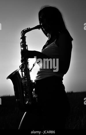 Silhouette einer Frau mit langen Haaren spielen ein Saxophon. Schwarz und Weiß Foto Stockfoto